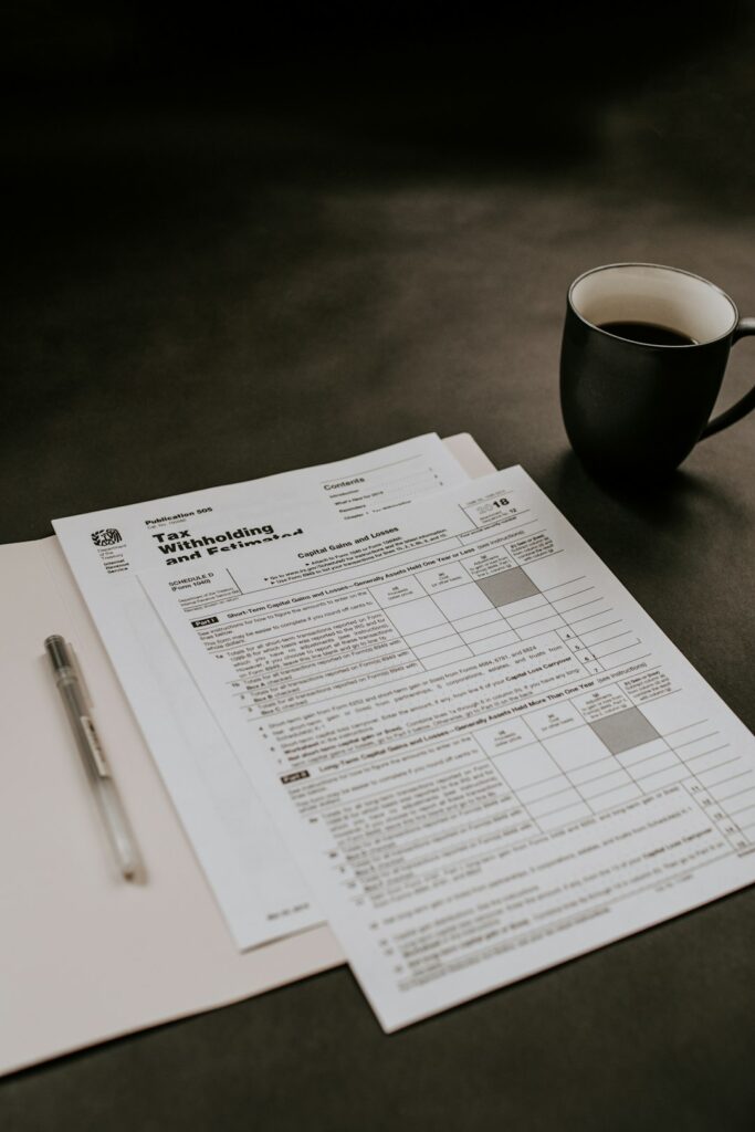 A person sorts tax forms, receipts, and labeled folders at a home desk.
