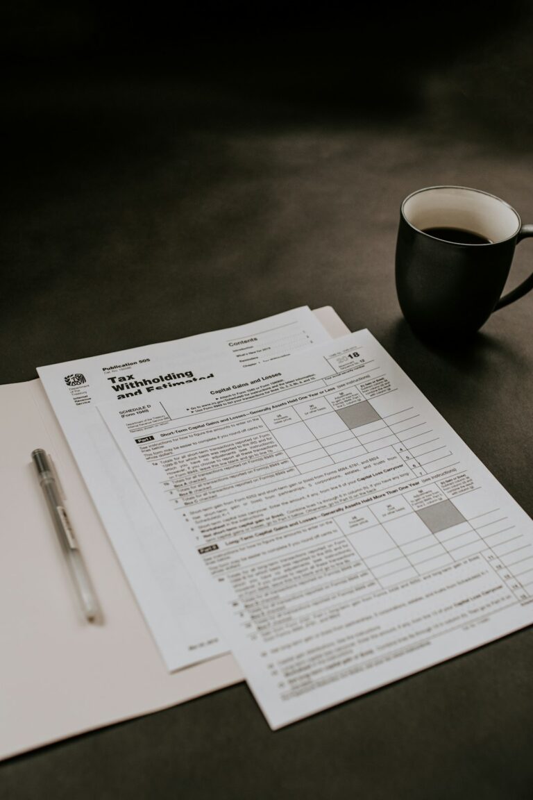 A person sorts tax forms, receipts, and labeled folders at a home desk.