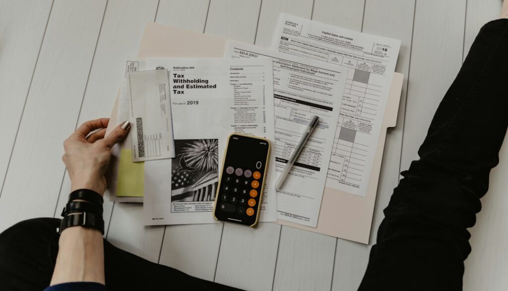 Freelancer reviewing receipts, mileage notes, and a laptop at a home office desk.