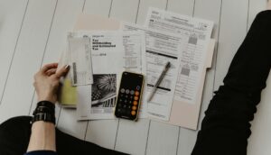 Freelancer reviewing receipts, mileage notes, and a laptop at a home office desk.
